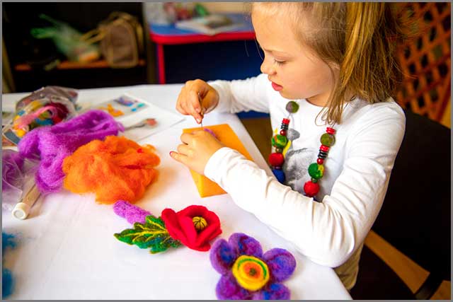 A little girl making a toy of wool felt