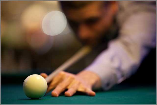 Pool table felt with a white cue ball and player in the background