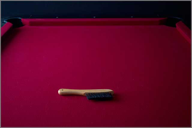 Pool table cleaning brush on a red felt fabric surface