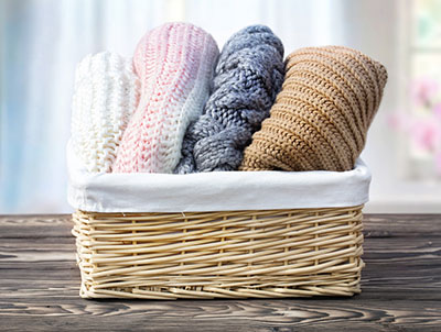 Knitted woolen clothes rolled in a basket