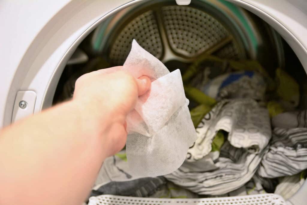 woman putting dryer sheet into a dryer