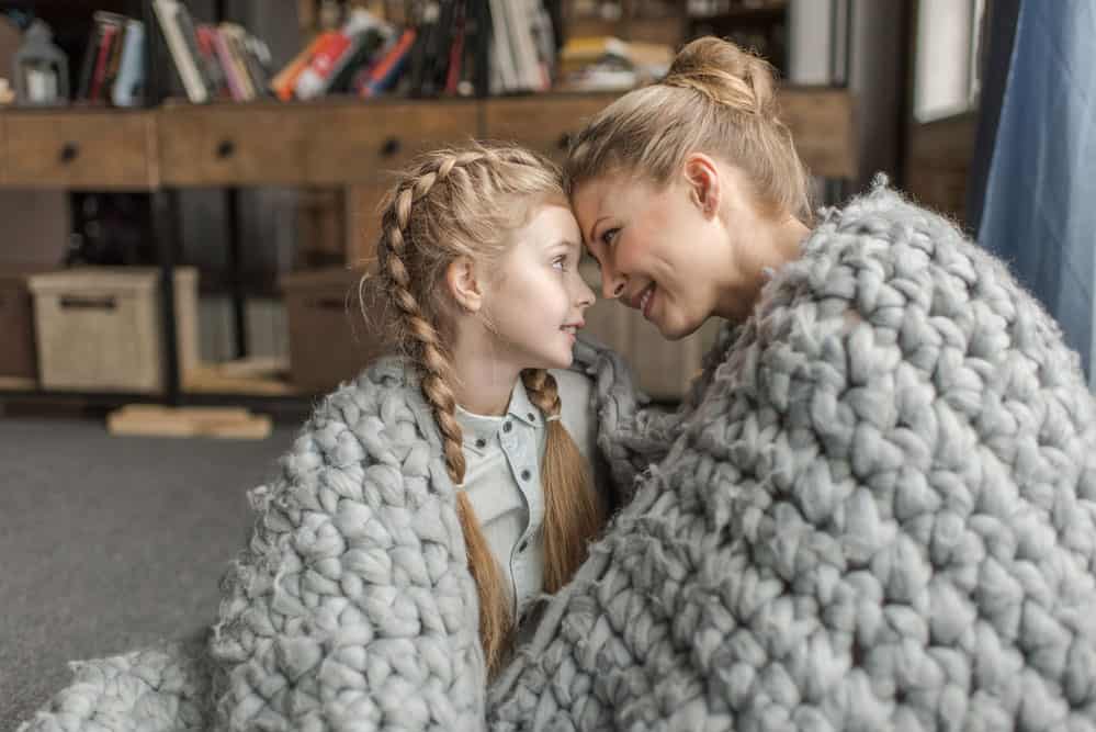 mother and daughter under merino wool blanket