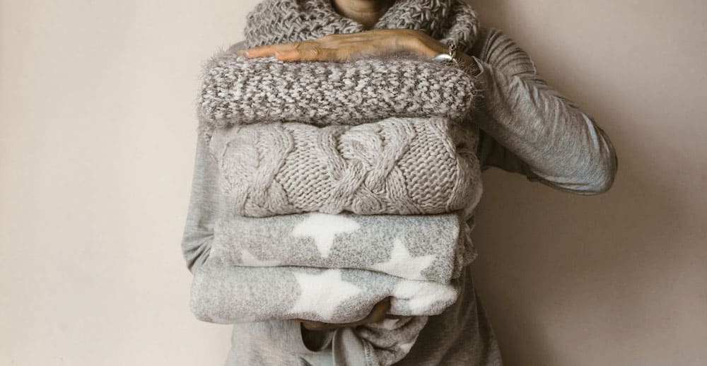 women holding a stack of wool garments