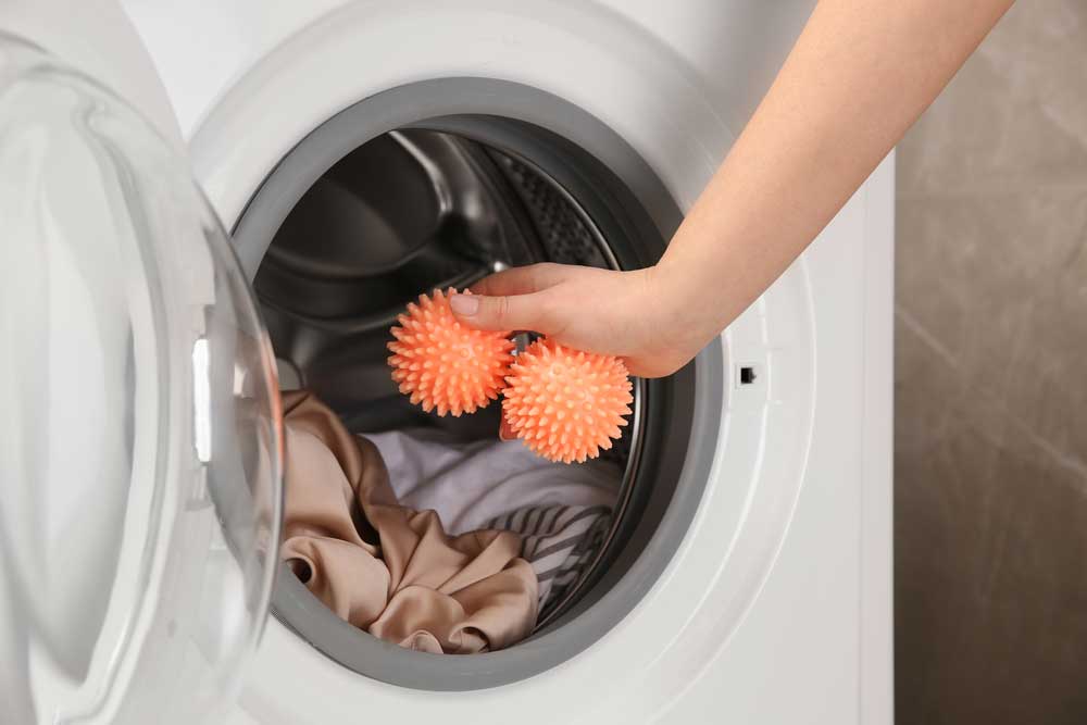 Lady inserting plastic dryer balls into the dryer