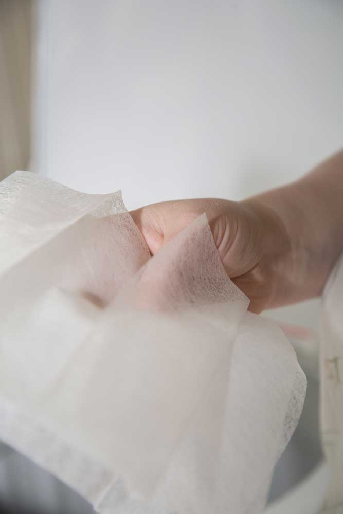 A lady's hand holding a few dryer sheets